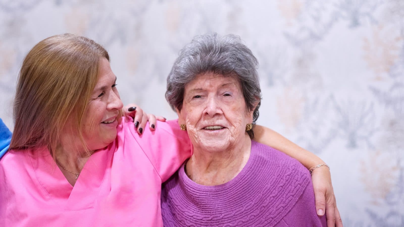 Cuidadora abrazando con cariño a una señora mayor