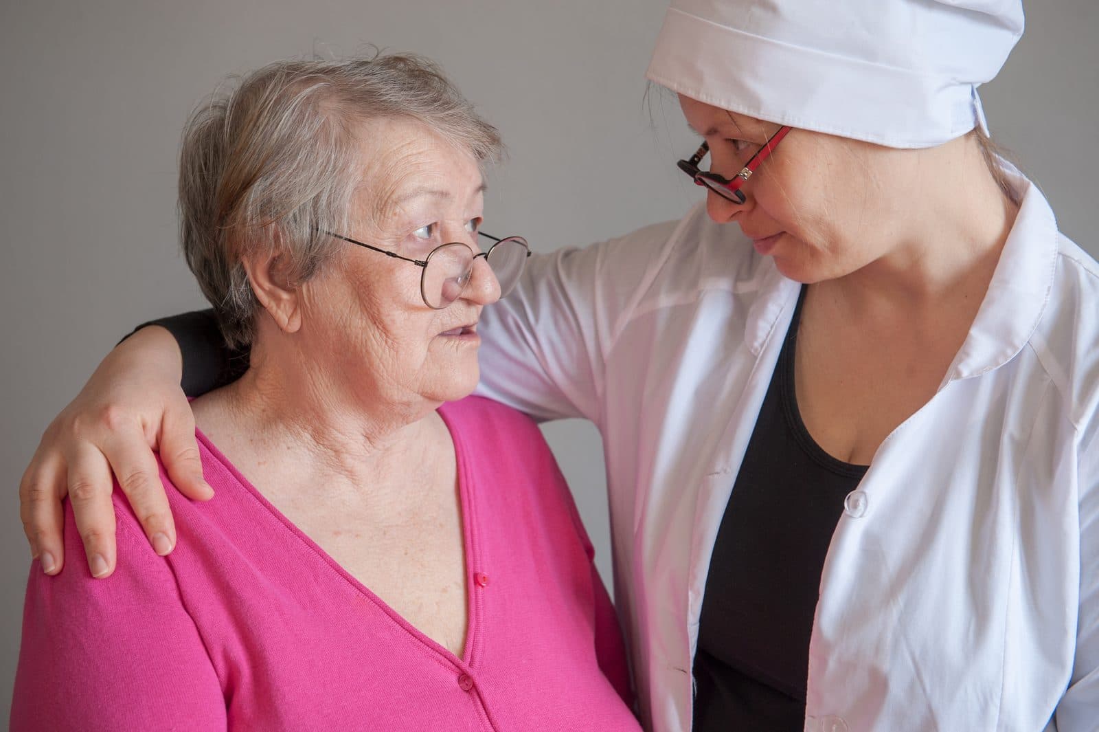 Profesional sanitaria atendiendo y consolando a una señora mayor