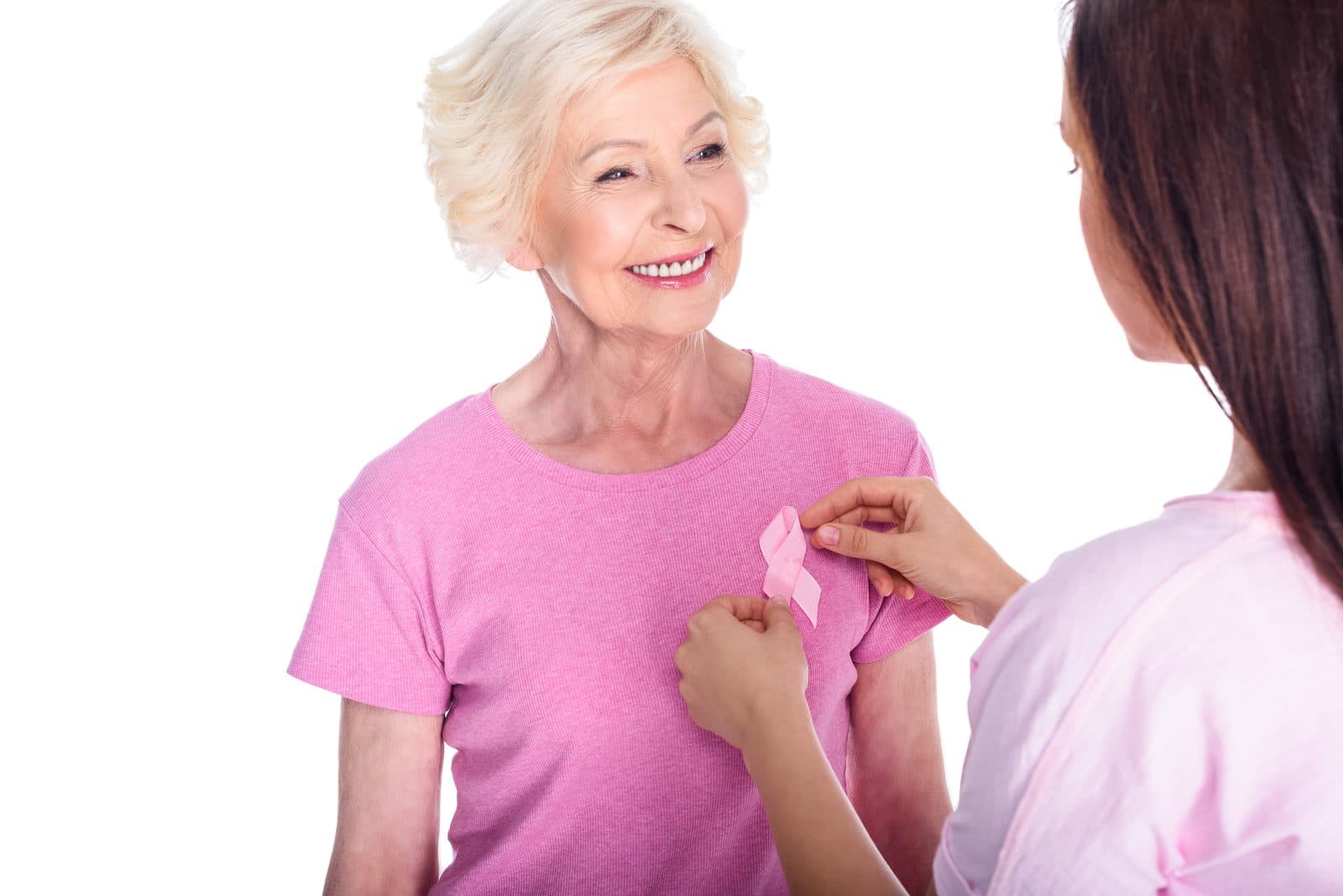 Señora mayor recibiendo un lazo rosa de manos de una mujer joven